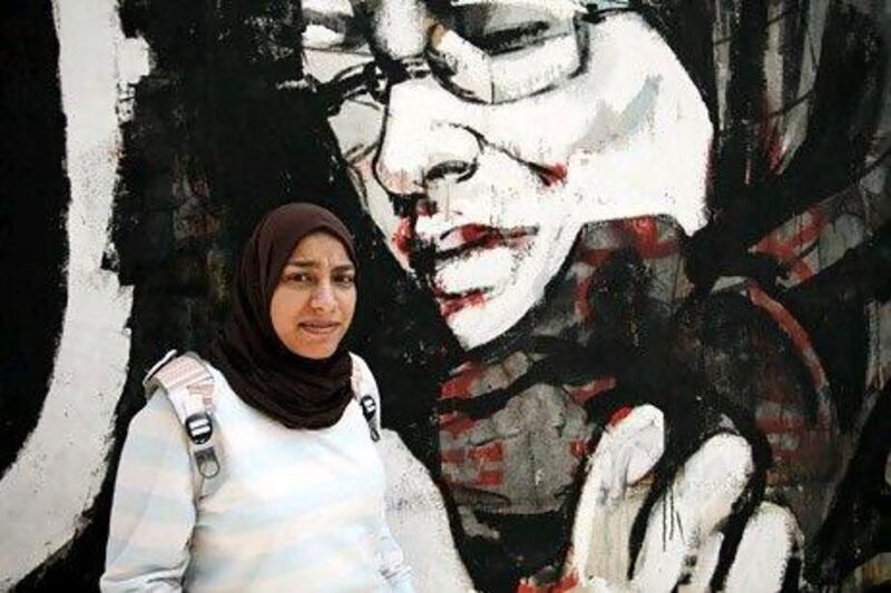 Norhan Aly, age 21, an Egyptian student, poses for photo in front of graffiti near Tahrir square, in downtown Cairo, Egypt, Saturday, June 2, 2012. (Photo/Tara Todras-Whitehill)