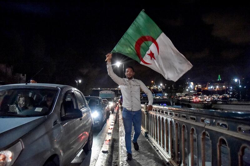 Algerian marches with a national flag during a demonstration in the centre of the capital Algiers on March 11, 2019, after President Abdelaziz Bouteflika announced his withdrawal from a bid to win another term in office and postponed an April 18 election, following weeks of protests against his candidacy.  Bouteflika, in a message carried by national news agency APS, said the presidential poll would follow a national conference on political and constitutional reform to be drawn up by the end of 2019. / AFP / RYAD KRAMDI                         
