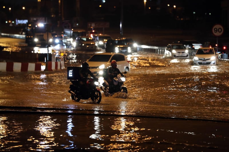 Dubai, United Arab Emirates - Reporter: N/A: Weather. Cars and motorbikes try to get through flooding on a roundabout near studio city. Saturday, March 21st, 2020. Dubai. Chris Whiteoak / The National