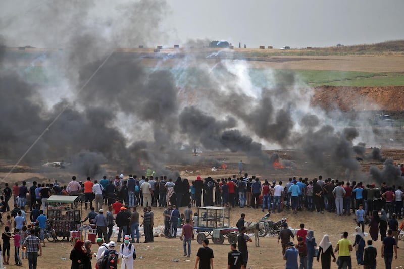 Palestinian protesters look at tear gas and smoke billowing from burning tyres, east of Gaza City, as Palestinians readied for protests over the inauguration of the US embassy following its controversial move to Jerusalem. Mohammed Abed / AFP