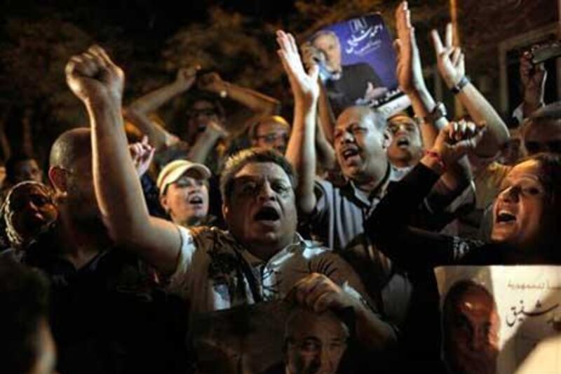 Egyptian supporters chant slogans and carry posters with pictures of presidential runoff candidate Ahmed Shafiq in front of his ransacked campaign headquarters in Cairo.