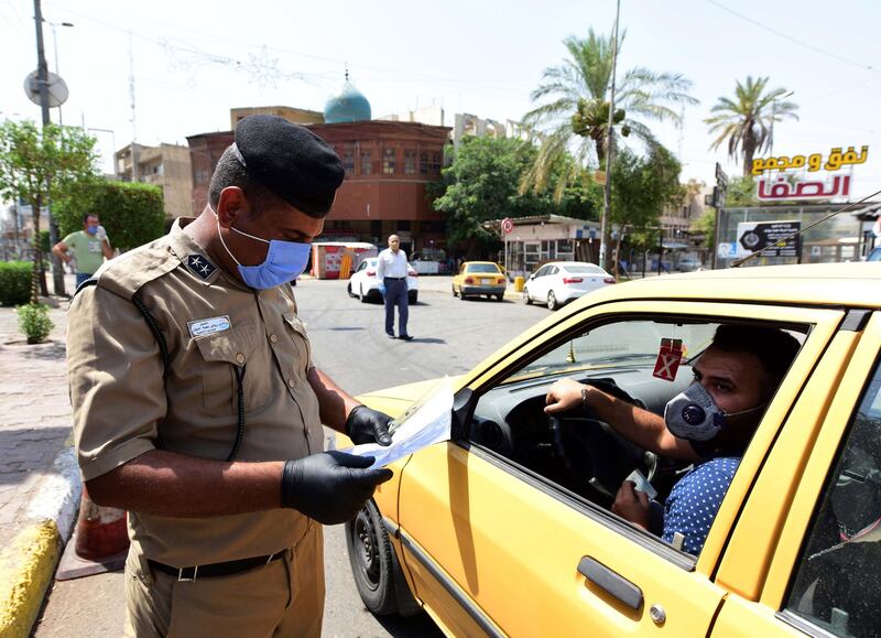An Iraqi policeman checks documents at a checkpoint during curfew as a part of coronavirus restrictions at the Adhamiya neighborhood in Baghdad, Iraq.  EPA