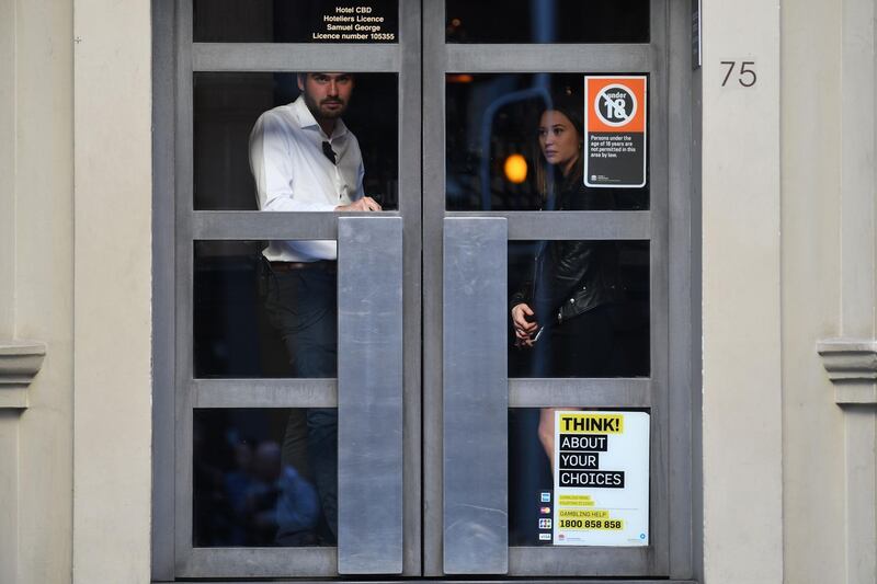 People look out from the interior of a hotel as police (not pictured) investigate the crime scene outside after a man stabbed a woman and attempted to stab others in central Sydney on August 13, 2019, before being pinned down by members of the public and detained by police. Police said the woman was in a stable condition and there were no immediate reports of other injuries, despite "a number of attempted stabbings by the same offender." / AFP / Saeed KHAN
