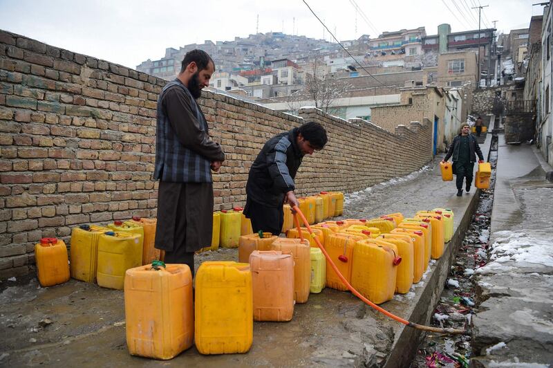 Afghan people fill containers with water from a pump in Kabul on January 30, 2019. / AFP / WAKIL KOHSAR
