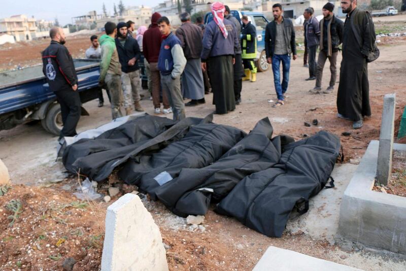 This photo provided by the Syrian Civil Defense White Helmets, which has been authenticated based on its contents and other AP reporting, shows Syrian citizens stand near dead bodies they were killed from airstrikes hit in Khan Sheikhoun, in the northern province of Idlib, Syria, Sunday, Dec. 17, 2017. Syrian activists say at least nine civilians have been killed in airstrikes on a residential area in the rebel stronghold northwestern province of Idlib. (Syrian Civil Defense White Helmets via AP)