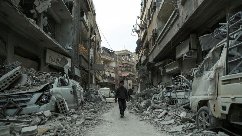 TOPSHOT - A picture taken on March 8, 2018 shows a Syrian child walking down a street past rubble from destroyed buildings, in the rebel-held town of Douma in the Eastern Ghouta enclave on the outskirts of Damascus. / AFP PHOTO / HAMZA AL-AJWEH