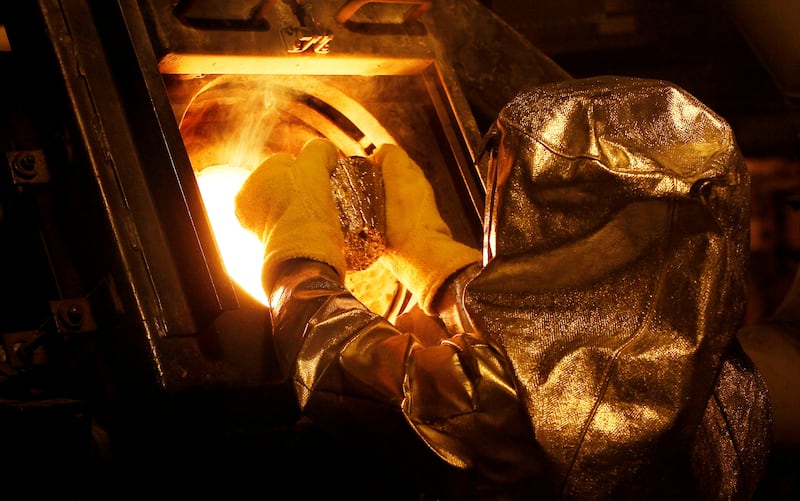 FILE PHOTO: Senior refinery technician Vincente Sandoval puts a gold "button" into a furnace to be further refined to form gold dore bars at Newmont Mining's Carlin gold mine operation near Elko, Nevada, U.S., May 21, 2014. REUTERS/Rick Wilking/File Photo