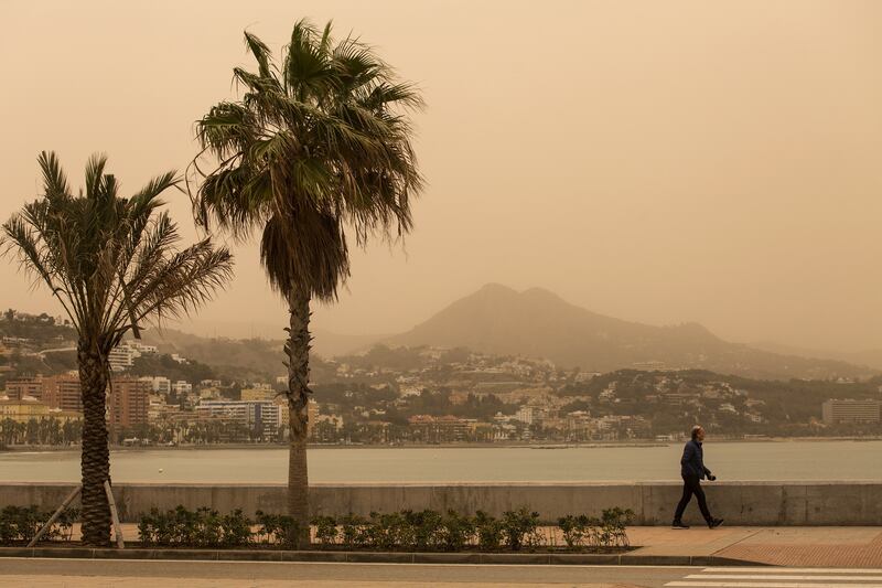 A man walks along a promenade in Malaga, Spain, as dust from the Sahara desert swept through the country propelled by storm Celia. EPA