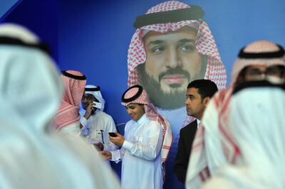 Saudi men chat in front of a poster of Saudi Crown Prince Mohammed bin Salman during the "MiSK Global Forum" held under the slogan "Meeting the Challenge of Change" in Riyadh, on November 15, 2017. 
The MiSK Global Forum brings together global CEOs international policymakers and heads of tech giants. / AFP PHOTO / FAYEZ NURELDINE