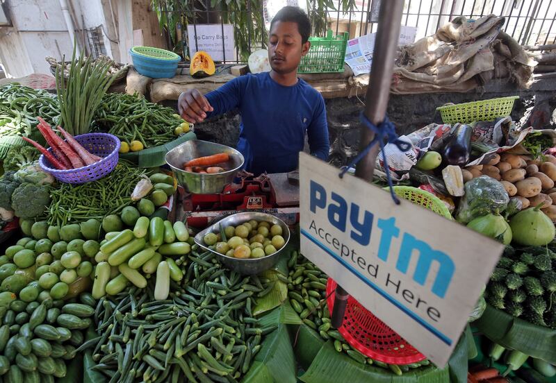 A vendor weighs vegetable next to an advertisement of Paytm, a digital payments firm, hanging amidst his vegetables at a roadside market in Mumbai, India, April 2, 2019. REUTERS/Francis Mascarenhas