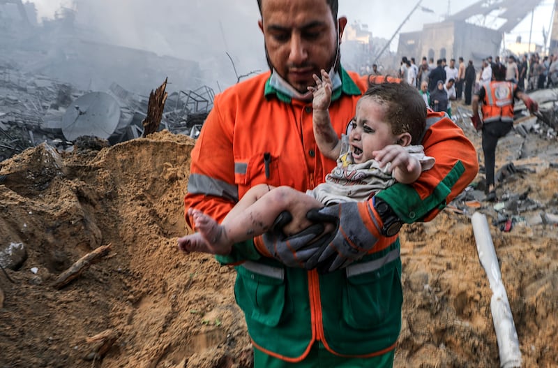 A Palestinian man carries a baby found in the rubble of a destroyed area following Israeli air strikes in Gaza city. EPA