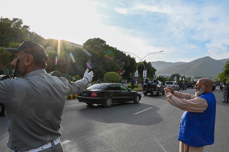 Security personnel escort Mr Khan's car to the Supreme Court in Islamabad. AFP