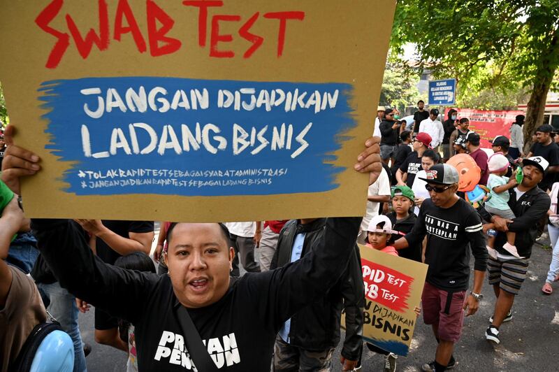 People take part in a protest calling for the rejection of a local government policy which requires workers to take rapid and swab tests to check for the coronavirus, in Denpasar on the Indonesia resort island of Bali.  AFP