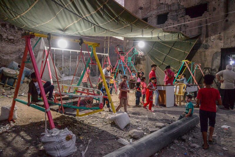 Iraqi children ride on swings in the old city of Mosul. AFP