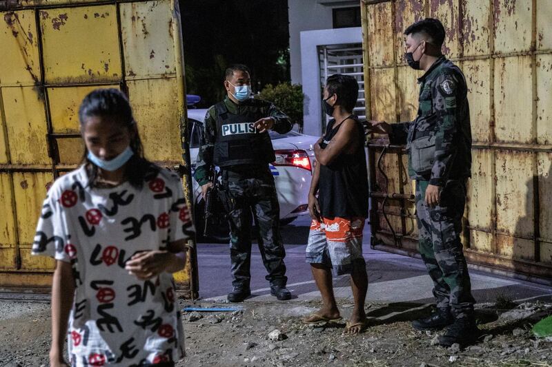 Armed police direct a curfew violator to a holding area as the government implements a new curfew in the country's capital. REUTERS/Eloisa Lopez