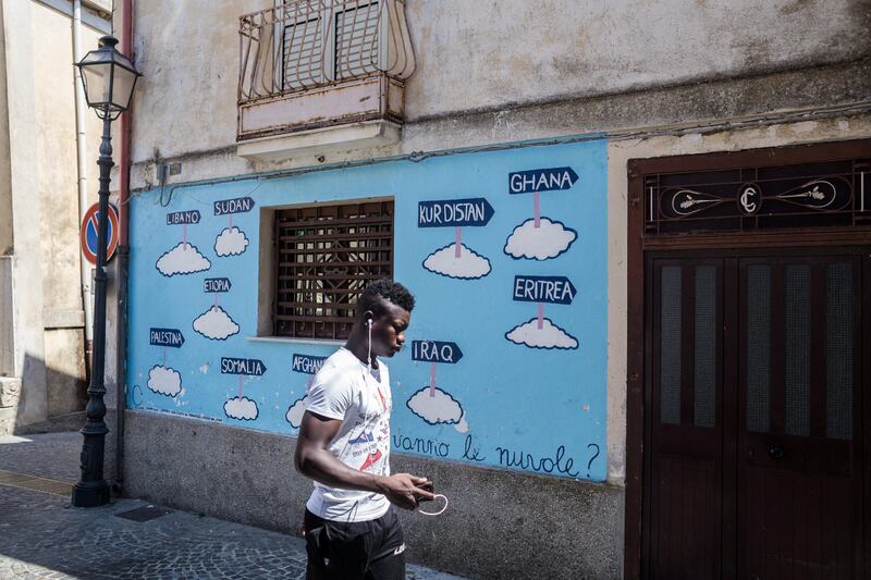 A man walks past a mural painted in support of migrants titled ‘where are the clouds going?’. The National/Giacomo Sini