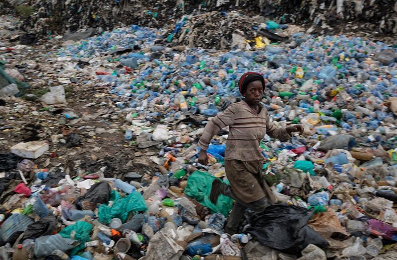 A young girl runs through a mound of sorted plastic bottles at the dump in the Dandora slum of Nairobi, Kenya. AP Photo