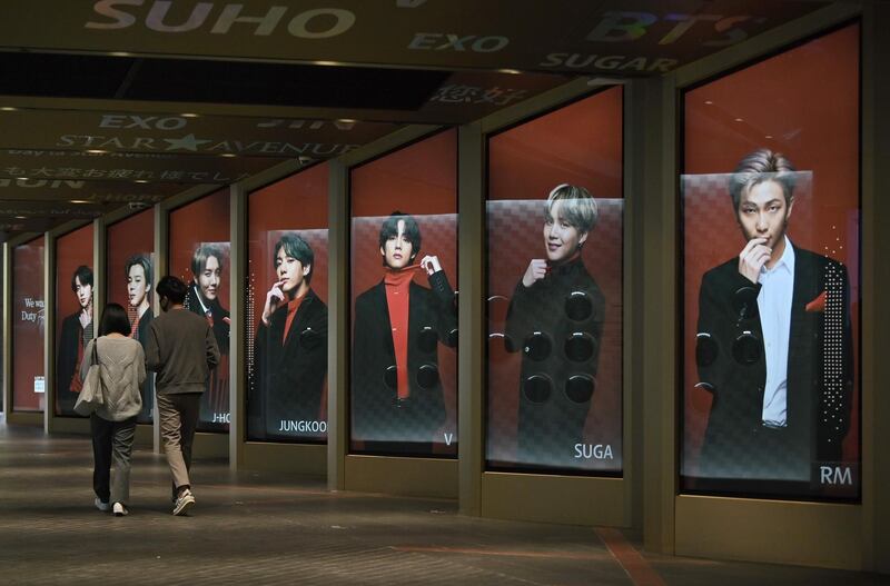 People walk past commercial posters showing BTS members outside a duty free shop in Seoul. AFP
