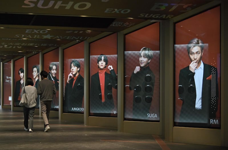 People walk past commercial posters showing BTS members outside a duty free shop in Seoul. AFP