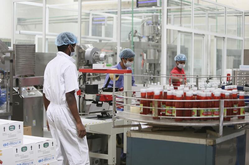 Workers oversee the tomato ketchup assembly line at the Chilly Willy manufacturing facility in Dubai, June 3, 2015.