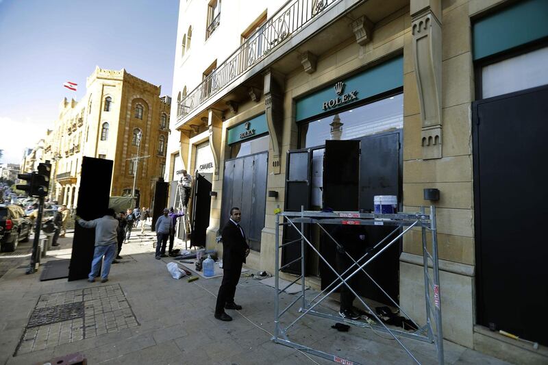 Workers fix iron shields on the windows of shops to protect them from damage during anti-government riots in the Lebanese capital Beirut's downtown district, on January 24, 2020. AFP