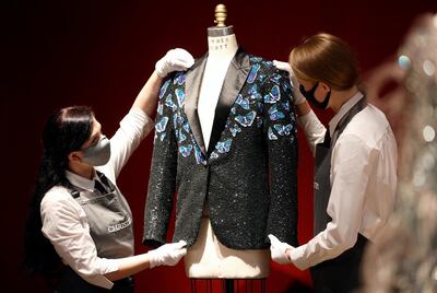 Gallery assistants pose for a photograph with the Butterfly jacket designed for Mick Jagger by designer L’Wren Scott at Christie’s in London, Britain, June 10, 2021. REUTERS/John Sibley
