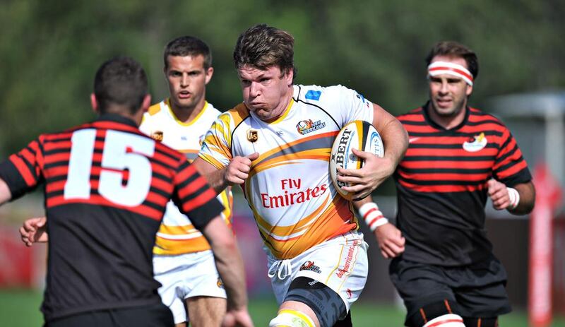 A Dubai Hurricanes ball carrier, in white, attempts to navigate past a group of Abu Dhabi Saracens. Abu Dhabi won 21-18 at The Sevens in Dubai City, Dubai on February 28, 2014. Jeff Topping for The National