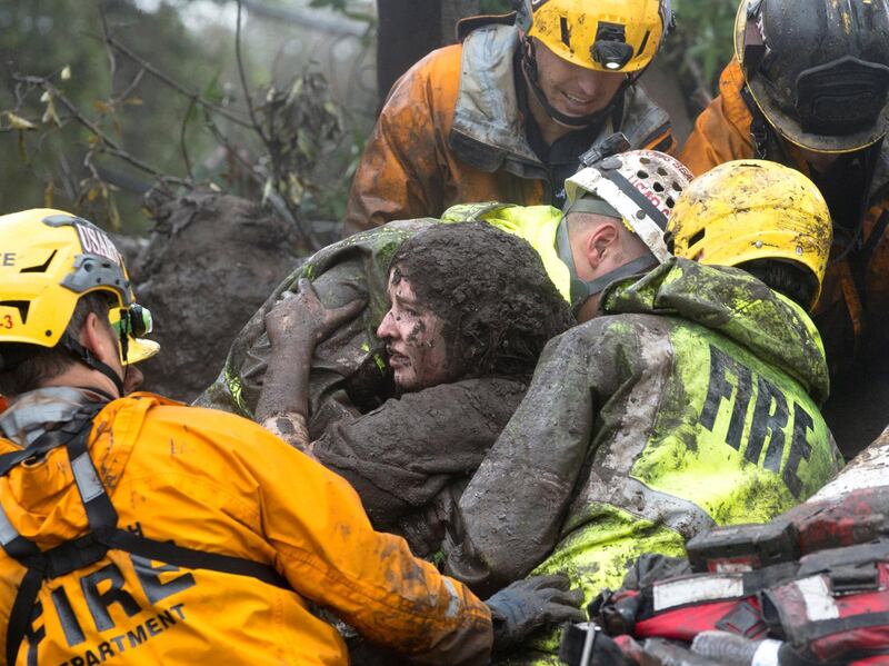 Emergency personnel carry a woman rescued from a collapsed house after a mudslide in Montecito, California. Kenneth Song / Santa Barbara News-Press via Reuters