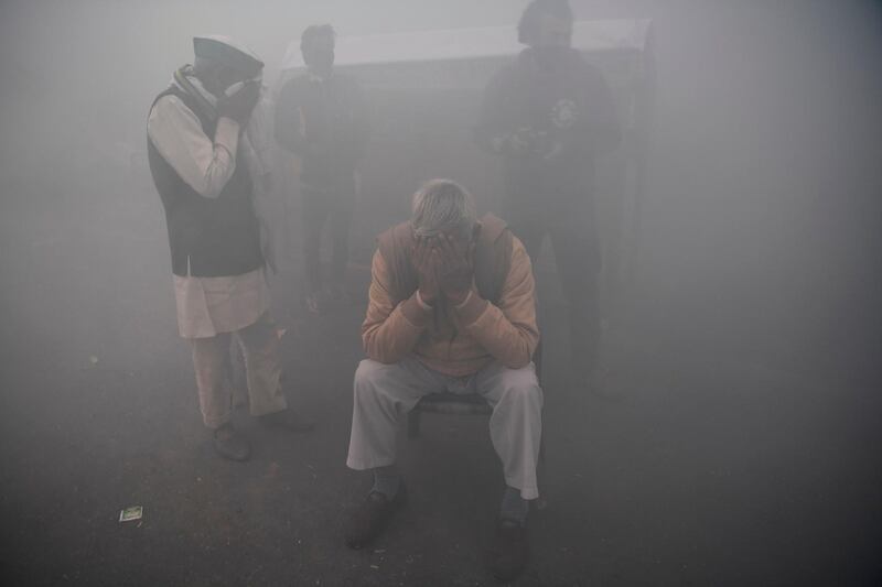 Farmers cover their faces, amid smoke during fumigation by the muncipal corporation, near a road block stopping farmers from marching to New Delhi to protest against the central government's  agricultural reforms.  AFP