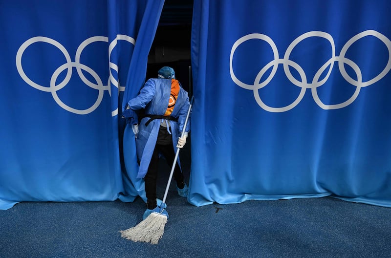 A staff member looks behind the curtains in preparation for the women's ice hockey semi-final between USA and Finland, at the Beijing Winter Olympics. AFP