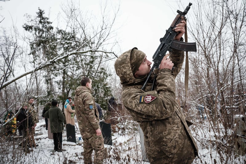 A Ukrainian troop fires a rifle during the burial of a soldier killed in action in Bakhmut. AFP