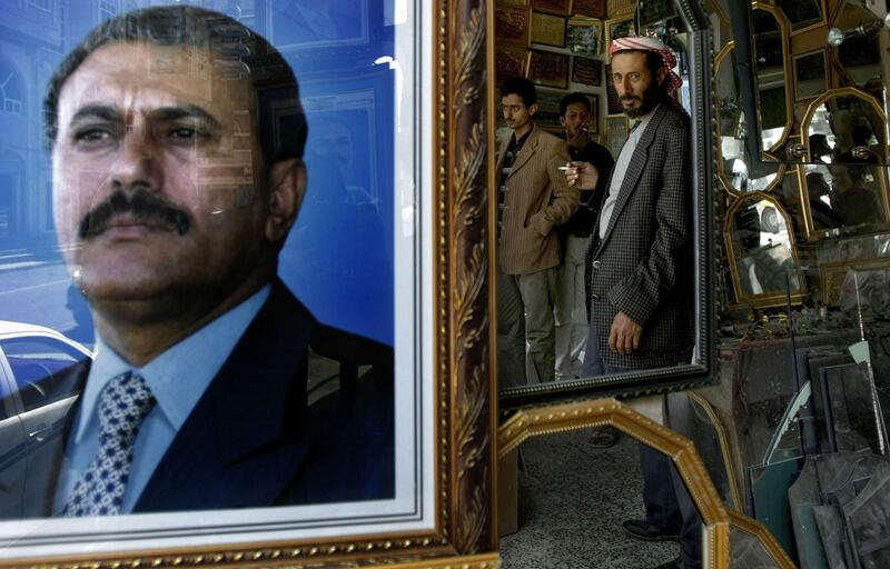 (FILES) This file photo taken on January 24, 2010 shows the reflection of Yemenis in a mirror next to a picture of Yemeni ex-president Ali Abdullah Saleh in Sanaa.
Yemen's ex-president Ali Abdullah Saleh, slain by his former rebel allies died aged 75 on December 4, 2017.

 / AFP PHOTO / MARWAN NAAMANI