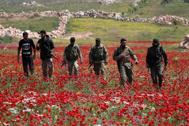 FILE PHOTO: Turkey-backed Syrian rebel fighters walk in a field of flowers in Jabal al-Zawiya in Idlib's southern countryside, amid concerns about the spread of the coronavirus disease (COVID-19), Syria April 15, 2020.  Picture taken April 15, 2020.  REUTERS / Khalil Ashawi / File Photo