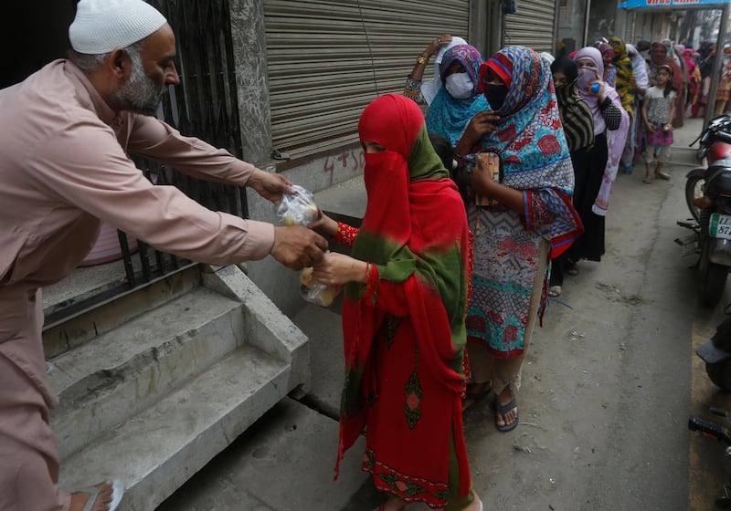 A man gives food to a woman  in Lahore, Pakistan. AP Photo