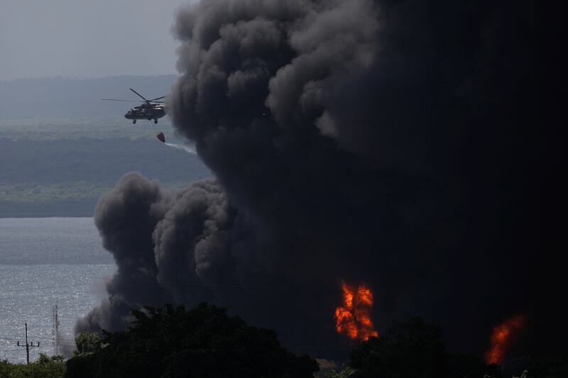 A helicopter drops water over burning fuel storage tanks that exploded near the supertanker port in Matanzas. Reuters