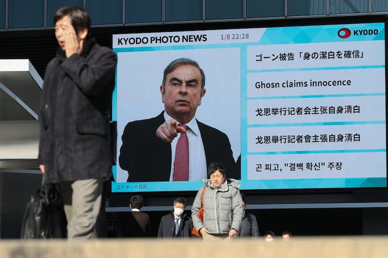 Pedestrians walk past a big screen showing images of former Nissan boss Carlos Ghosn in a news program on January 09. Getty Images