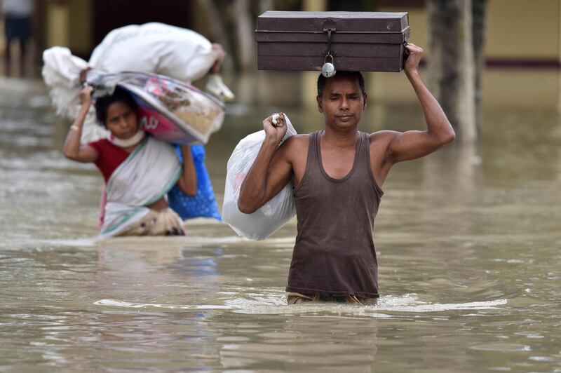 Indian villagers wade through flood waters. Biju Boro / AFP Photo