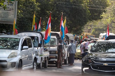 Supporters of the Myanmar military gather near trucks adorned with the military flag, Buddhist religious flag and national flag Monday, Feb. 1, 2021, in Yangon, Myanmar. Myanmar military television said Monday that the military was taking control of the country for one year, while reports said many of the country's senior politicians including Aung San Suu Kyi had been detained. (AP Photo/Thein Zaw)