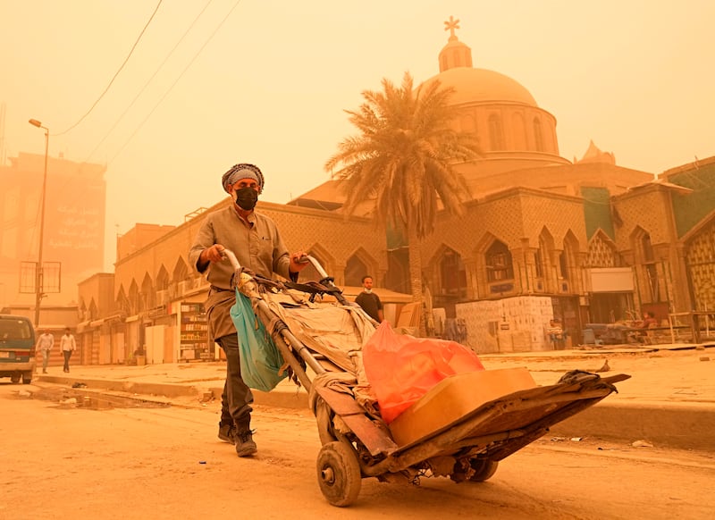 A man wearing a protective mask pushes a cart during the dust storm in Baghdad. AP