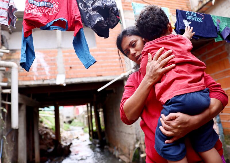 Francisca Cristiane carries her son  Artur outside her home in the Brasilandia neighborhood in Sao Paulo, Brazil. She said she won't send her children to school because of Covid-19 fears.