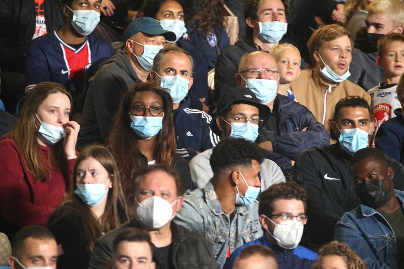 Fans wearing protective face mask watch the French L1 football match between Paris Saint-Germain (PSG) and ES Troyes.