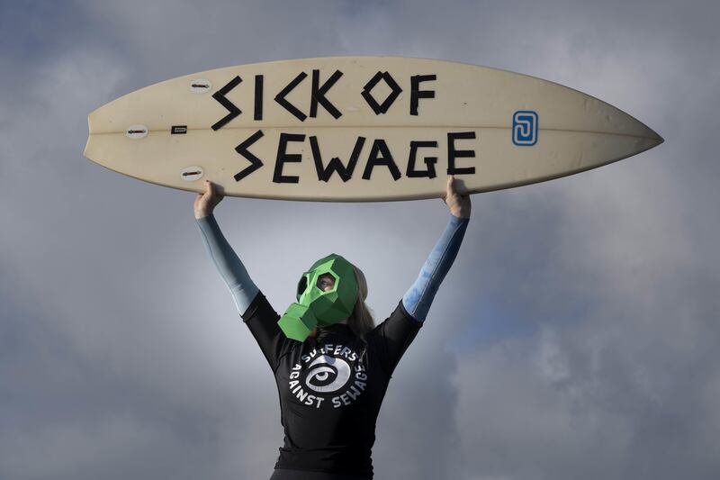 A representative from Surfers against Sewage protests against sewage discharges at an overflow pipe on Long Rock Beach in Penzance, Cornwall. PA