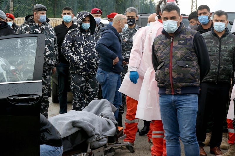 Members of the Lebanese security forces watch as medics remove the body of Lokman Slim from the car in which he was found dead with gunshot wounds on February 4, 2021. AFP