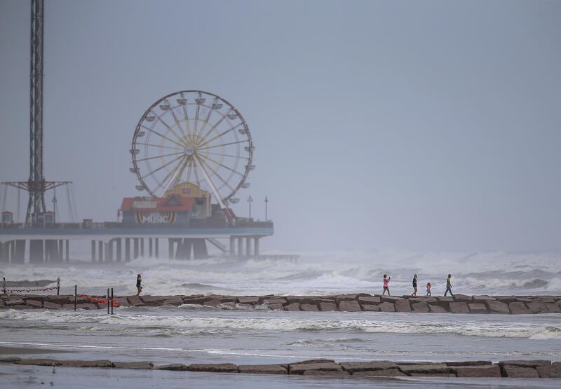 People walk along a jetty as waves roll in from approaching Hurricane Laura in Galveston, Texas. AFP