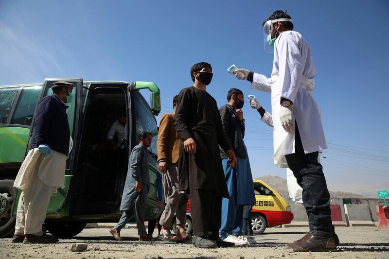 Afghan health workers measure the temperature of bus passengers in an effort to prevent the spread of the coronavirus, as they enter Kabul trough the city's western gate, on March 22, 2020. AP Photo