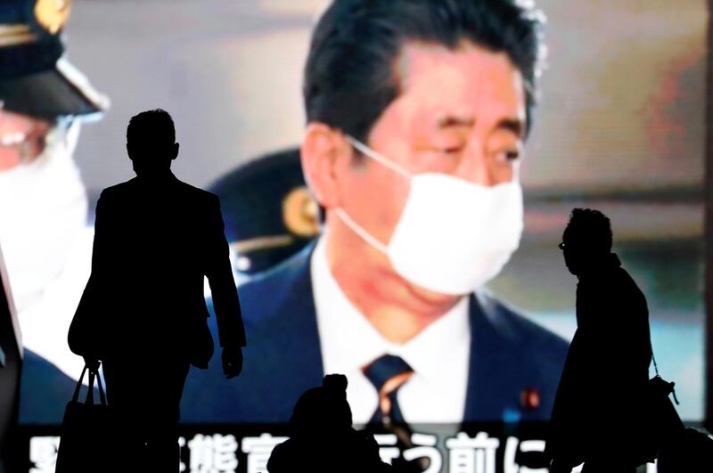 Passersby are silhouetted in front of a giant screen reporting Japan's Prime Minister Shinzo Abe and Japan's response to the coronavirus disease (COVID-19) outbreak in Tokyo, Japan. REUTERS