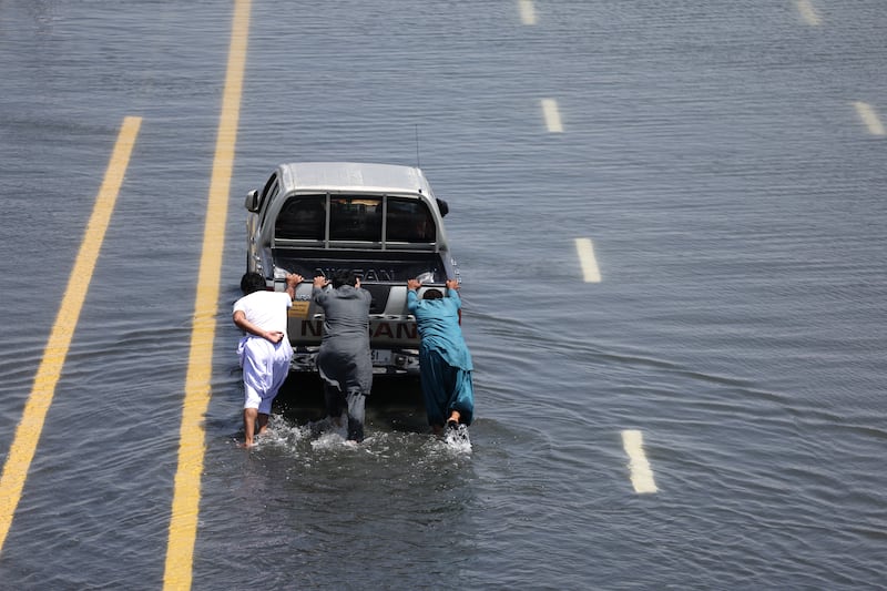 People push a stalled car on a flooded Dubai highway on April 18. With all the indicators pointing towards more rain over the UAE in the near future, it is important to adapt the country’s infrastructure to this new reality. Getty Images