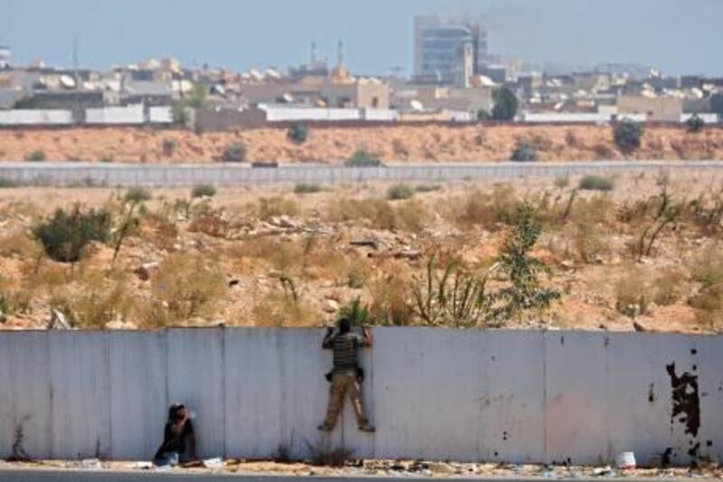 Rebel fighters observe the fighting near the main Moammar Gadhafi compound in Bab Al-Aziziya district in Tripoli, LIbya, Tuesday, Aug. 23, 2011, where some of the heaviest fighting took place. The compound, which has been heavily damaged by NATO airstrikes, has emerged as one of the centers of government resistance since tanks rolled out and began firing at rebels trying to get in.(AP Photo/Sergey Ponomarev) *** Local Caption ***  APTOPIX Mideast Libya.JPEG-0f8ef.jpg