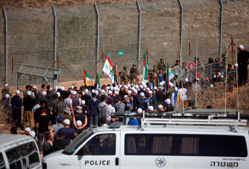 Druze men residing in Israel hold their community's flag after they heard about clashes in the Syrian Druze village of Hadar, on November 3, 2017 in the Israeli-annexed Golan Heights.

A suicide car bomb attack killed nine people in the government-held village of Hadar in Syria's Golan Heights, state media said, reporting clashes between government forces and rebels afterwards.
 / AFP PHOTO / JALAA MAREY