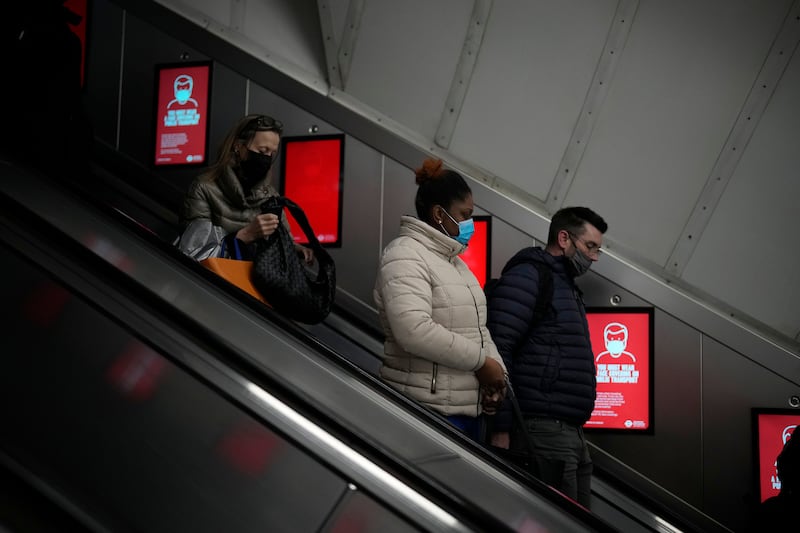 People wearing face masks pass electronic signs telling people they must wear masks on public transport, at Bond Street underground station in London. AP